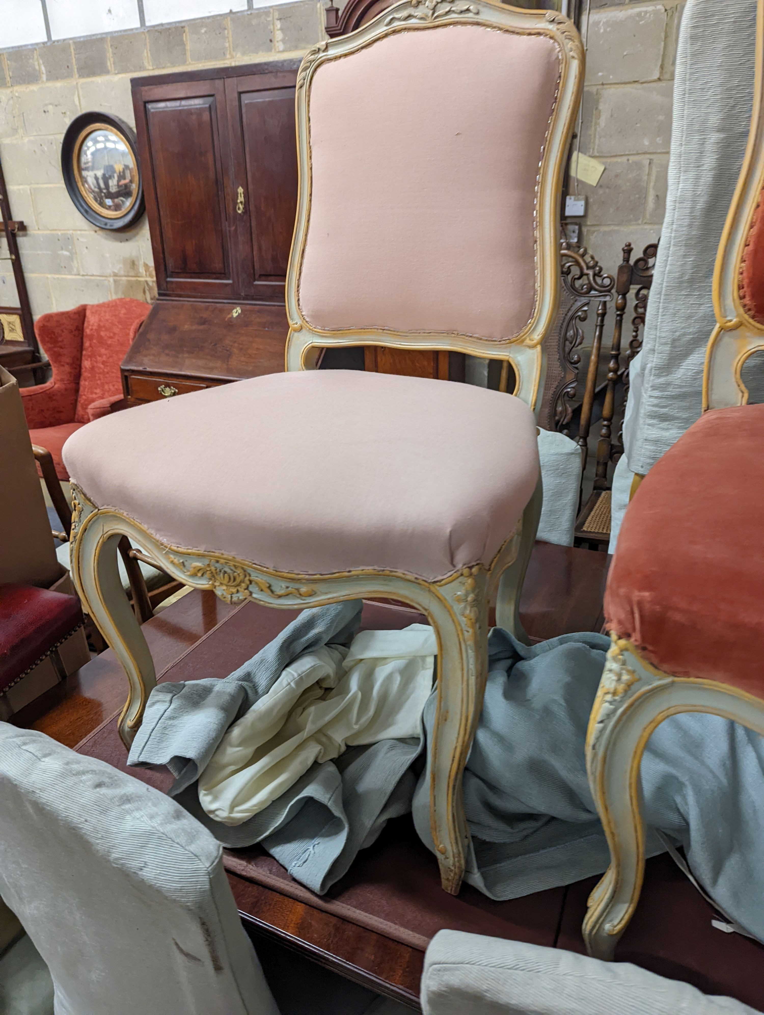 A set of fourteen French Louis XV style painted upholstered dining chairs with loose covers